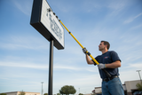 Man installing changeable sign letters on a pylon sign with a  changeable sign letter pole 
